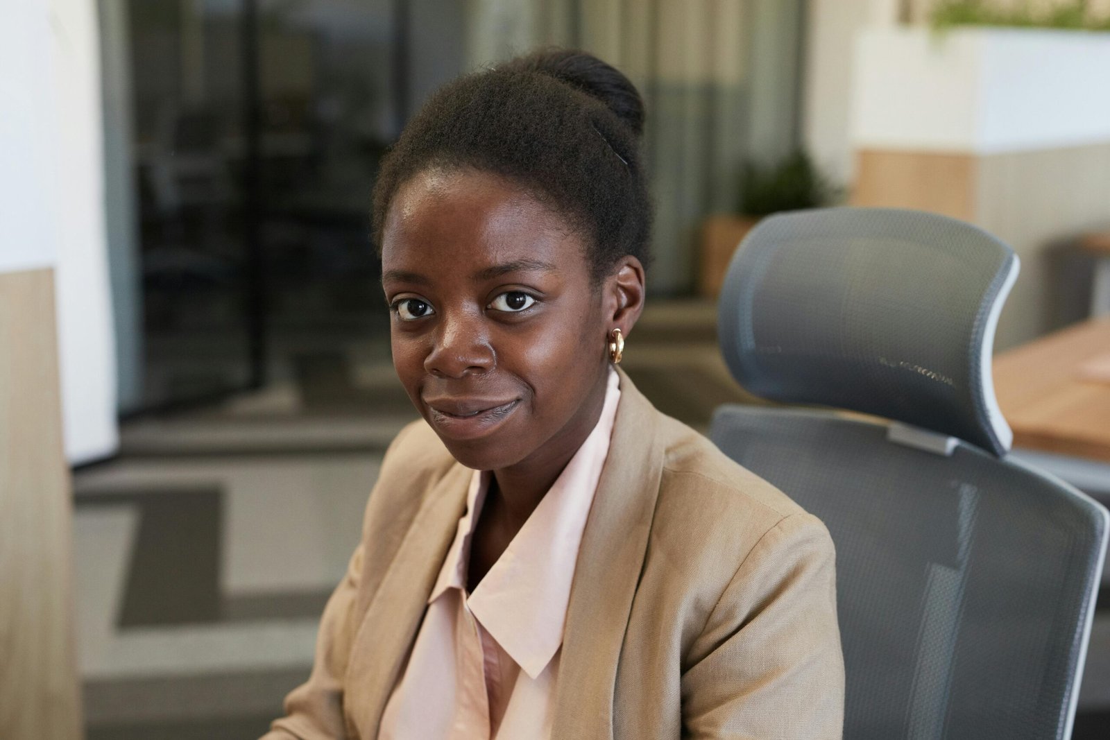 Professional woman smiling confidently while seated in a modern office.