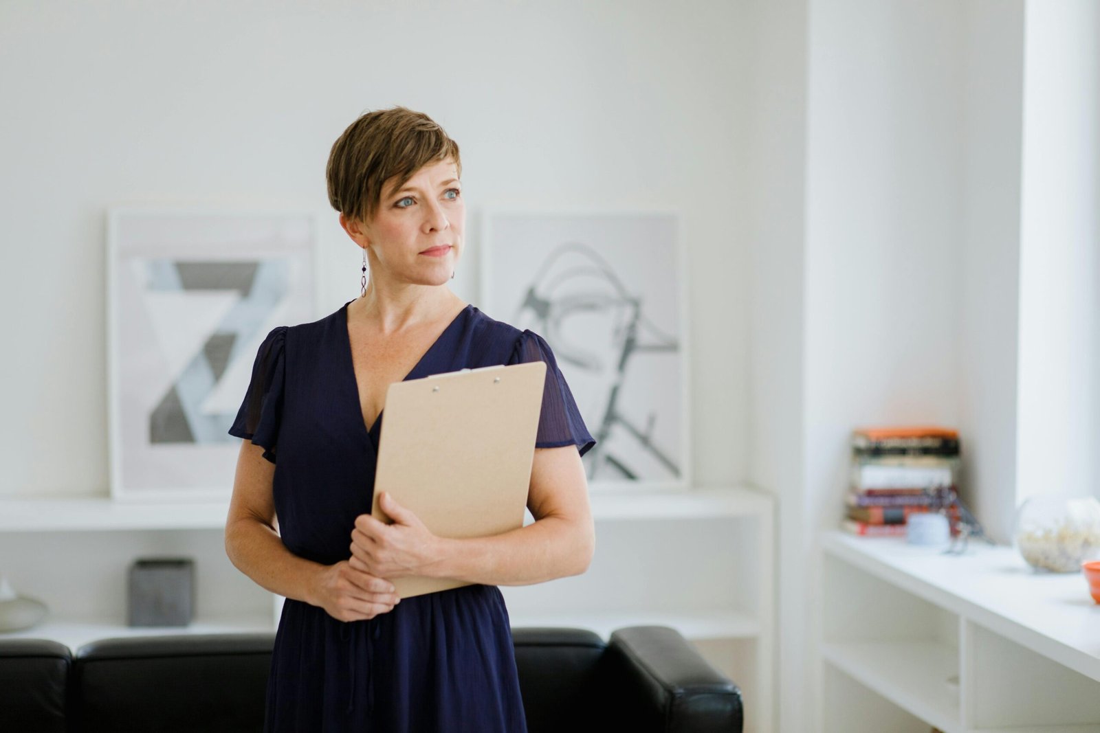 A professional woman with short hair holds a clipboard, exemplifying confidence in an indoor office setting.